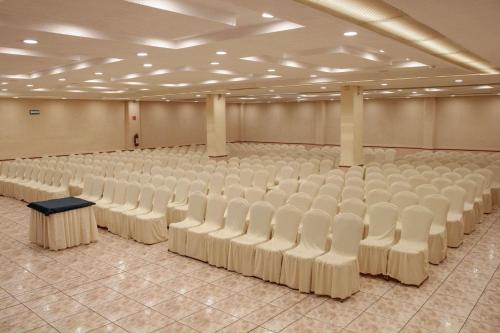 an empty hall with rows of white chairs at Radisson Hotel & Convention Center Toluca in Toluca