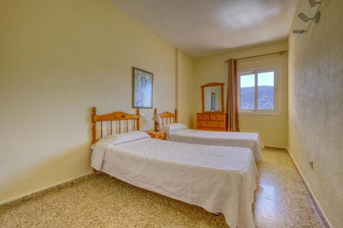 une chambre avec deux lits et une fenêtre dans l'établissement Apartamentos Costamar, à Los Cristianos