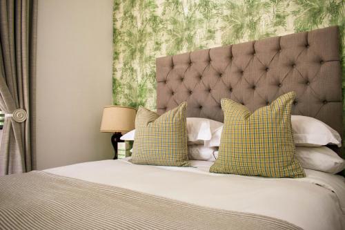 a bedroom with a bed with green and white pillows at Van der Stel Manor in Stellenbosch