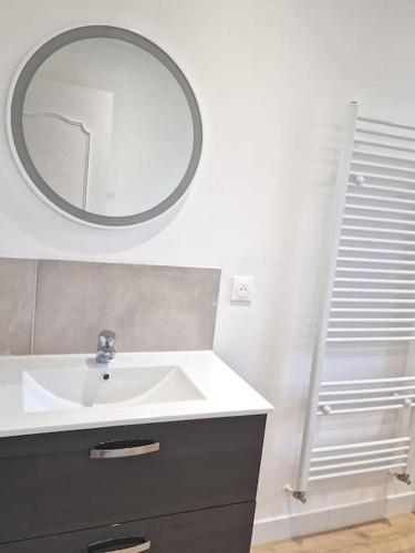 une salle de bain avec un lavabo et un miroir au mur dans l'établissement Maison à Aurillac - 3 chambres - Arrivée autonome, à Aurillac