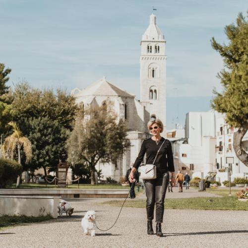 a woman walking a white dog on a leash at Liddo Boutique hotel in Barletta