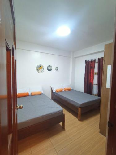 two beds in a small room with a door at 017 Baguio Transient in Baguio