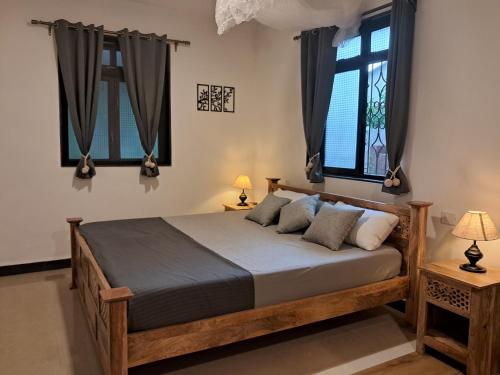 1 dormitorio con 1 cama de madera y 2 ventanas en Jangala Baga Beach - French welcome, tropical garden, close to the beach, en Arpora