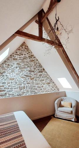 - une chambre mansardée avec un lit et un mur en pierre dans l'établissement Maison de contes en amoureux, à Taden
