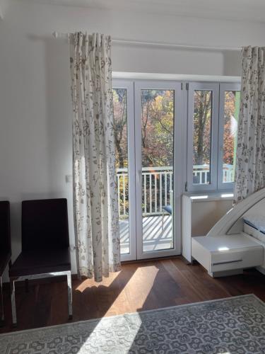 a bedroom with a bed and a balcony with windows at Privat Zimmer Sanela in Payerbach