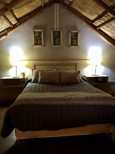 a bedroom with a large bed with two lamps at La Aldea in San Rafael