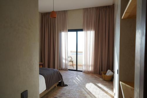 a bedroom with a bed and a large window at Loued Surf Lodge in Imsouane