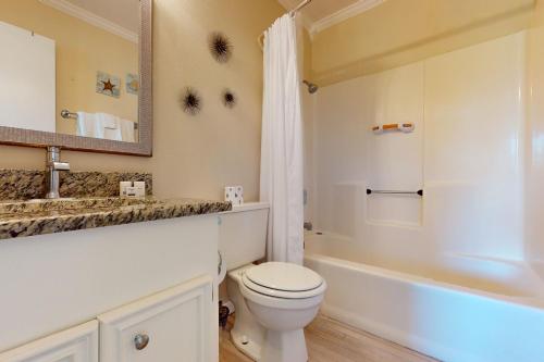 a bathroom with a toilet and a sink and a mirror at Unsearchable Colony V in Port Aransas