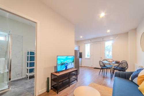 un salon avec une télévision et une table avec des chaises dans l'établissement Le cantonnement Angoumois, à Angoulême