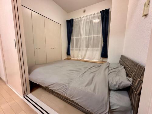 a small bedroom with a bed and a window at 411札幌駅7分と大通駅徒歩6分で好立地な都心を満喫でき綺麗な部屋で快適が生活が実現 in Sapporo