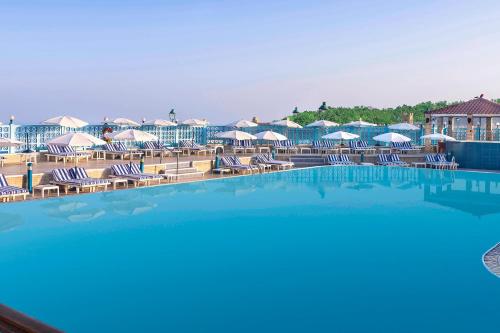 a swimming pool with chairs and umbrellas at a resort at Sheraton Montazah Hotel in Alexandria