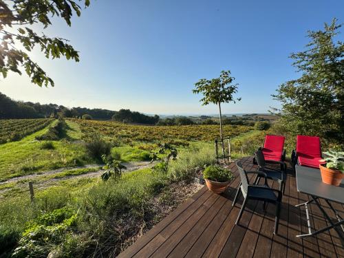 two chairs and a table on a wooden deck looking at a field at Le Ponant in Vaison-la-Romaine