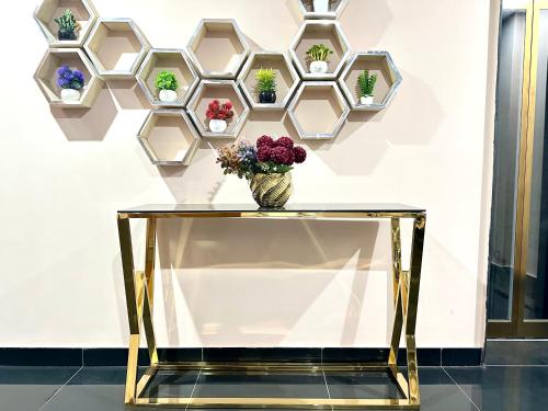 a glass table with a vase of flowers on a wall at Mukhtar Homes Bahria Town Lahore in Lahore