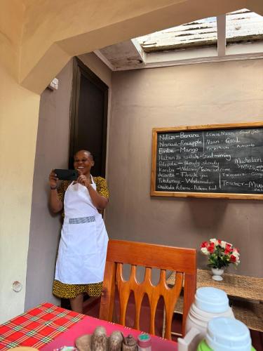 a woman standing in a restaurant with a chalkboard at Kisanga Homestay in Moshi