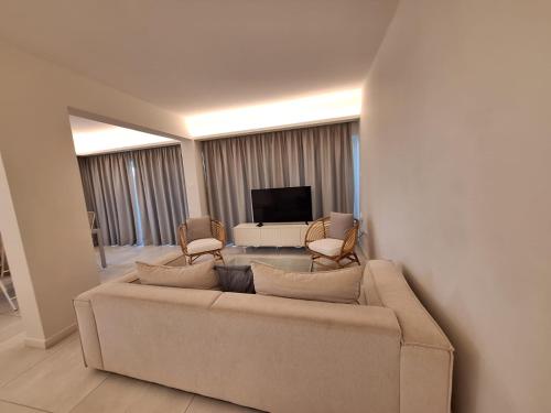 a living room with a couch and chairs and a television at Emerald Suites in Protaras