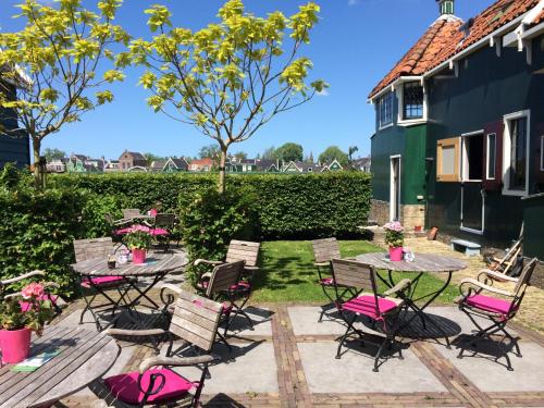 a patio with tables and chairs with pink cushions at Stay overnight at Windmill Village Zaanse Schans - Amsterdam in Zaandam