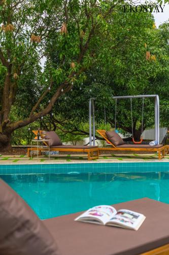 a swimming pool with a table with books on it at EKOSTAY - Amanta Palms 6BHK in Karjat
