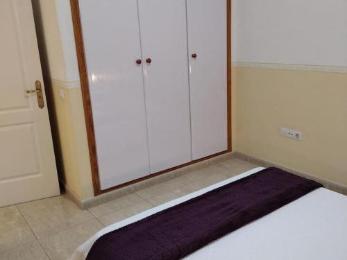 a bed in a room with white cabinets at 1A Apartment Abrigos, Wifi and balcony in Los Abrigos