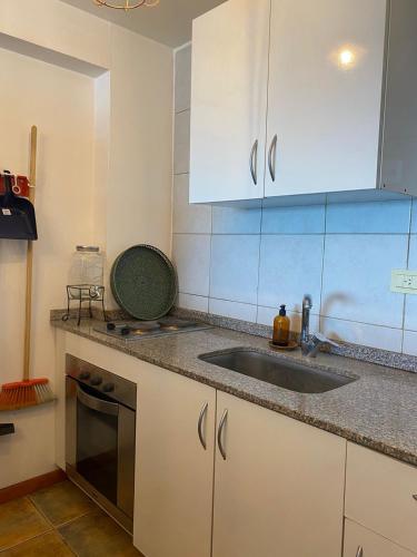 a kitchen with white cabinets and a sink at Libres del Sud & La Costa in Mar del Plata