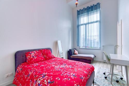 - une chambre avec un lit rouge et une chaise dans l'établissement Pablo Picasso - Appt à 30min de Montmartre, à Saint-Ouen