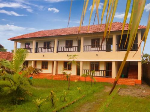 a house with a red roof and a green yard at Gram Bangla Retreat in Kolkata