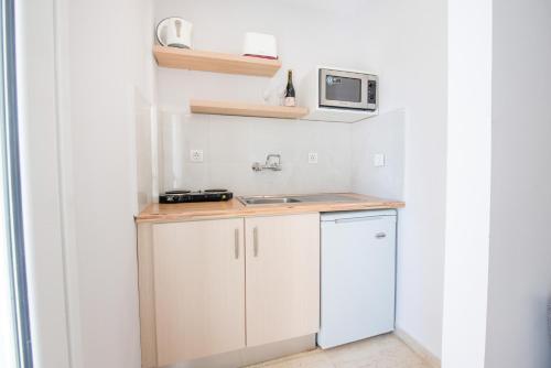 a small kitchen with white cabinets and a microwave at KORINA APART HOTEL KAVOS in Kavos