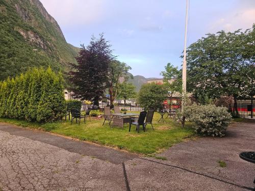 a park with chairs and a table in the grass at Eides Hotel in Høyanger