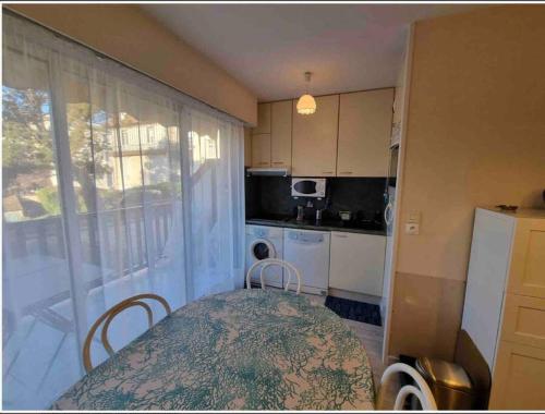 une petite cuisine avec une table et une fenêtre dans l'établissement Athena Proche plage Centre cabourg, à Cabourg