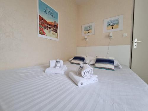 - un grand lit blanc avec des serviettes et des oreillers dans l'établissement Athena Proche plage Centre cabourg, à Cabourg