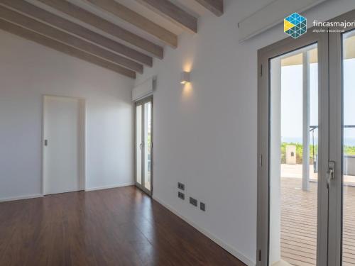 an empty living room with white walls and wood floors at Sa cova blanca in Cala Pi