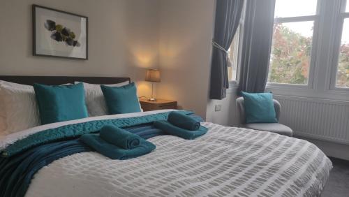 a bedroom with a large bed with blue pillows at Elegant Malvhina Retreat on the Malvern Hills in Great Malvern