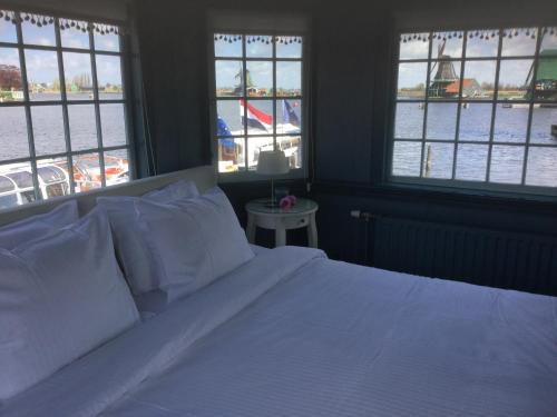a bedroom with a bed with white sheets and windows at Stay overnight at Windmill Village Zaanse Schans - Amsterdam in Zaandam
