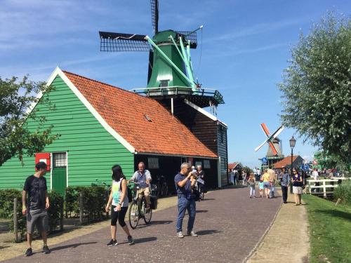 a group of people standing in front of a windmill at Stay overnight at Windmill Village Zaanse Schans - Amsterdam in Zaandam