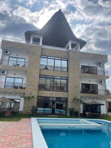 a large building with a swimming pool in front of it at Mawe Zuri Resort in Watamu