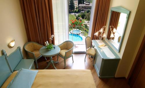 a room with two beds and a table and a window at Hotel Savoy Palace - Tonelli Hotels in Riva del Garda