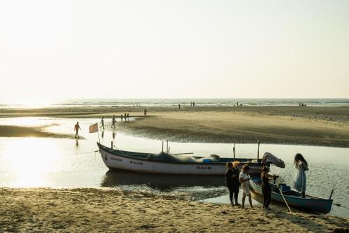 a group of people standing next to a boat on the beach at Jolene's Mandrem in Mandrem