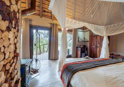 1 dormitorio con 1 cama en una habitación con troncos en Makalali River Lodge, en Hoedspruit