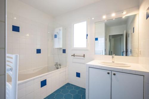 La salle de bains blanche est pourvue d'une baignoire, d'un lavabo et d'un miroir. dans l'établissement Villa Dahlia à deux pas de la plage PYLA SUR MER, à La Teste-de-Buch