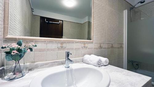 a bathroom with a sink and a vase of flowers at Mshome Sierra Nevada Monachil in Monachil