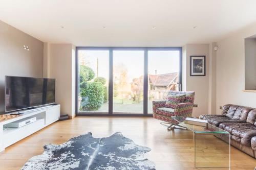 a living room with a couch and a flat screen tv at Woodside, surrounded by woodland and beautiful gardens in Wrington
