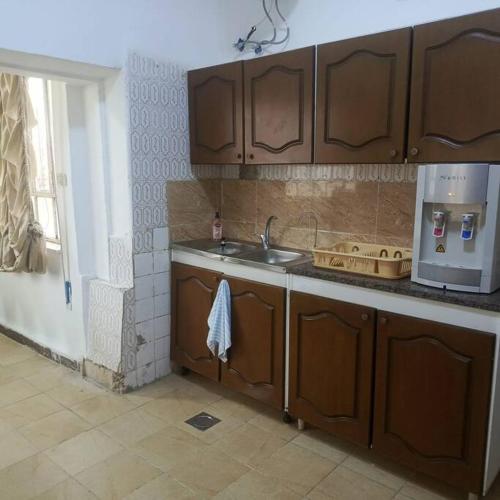 a kitchen with wooden cabinets and a sink and a stove at B Beitna in Amman