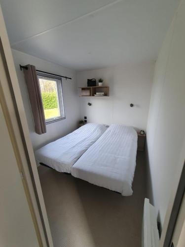 a bedroom with a large white bed with a window at Lodge geschikt voor 4 personen in Wijster