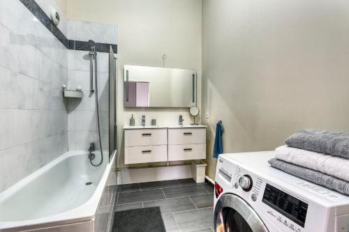 La salle de bains est pourvue d'un lave-linge et d'une baignoire. dans l'établissement La Plume d'Hugo - Appt Duplex pour 8, à Saint-Ouen
