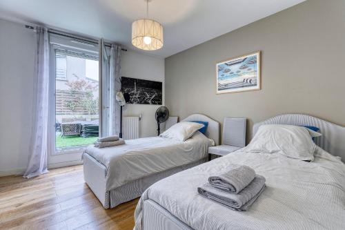 deux lits dans une chambre avec une fenêtre dans l'établissement La Plume d'Hugo - Appt Duplex pour 8, à Saint-Ouen