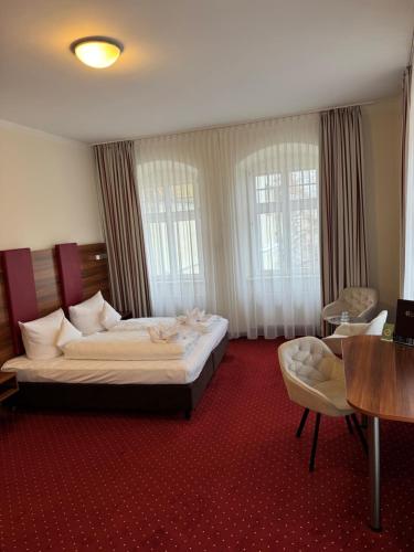 a hotel room with a bed and a table and chairs at Hotel Schwibbogen Altstadt & Appartements in Görlitz