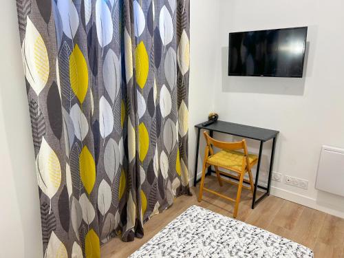 Cette chambre comprend une table, une chaise et une télévision. dans l'établissement Air-Conditioned Apart 10 Pers,40min Paris, Orly 20min, Disneyland 40min, à Saint-Pierre-du-Perray