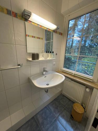 a white bathroom with a sink and a window at Loh Apartments - Wald.Natur.Ruhe. in Undeloh