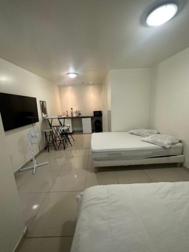 Habitación blanca con cama y TV de pantalla plana. en Appartement beau livry, en Livry-Gargan