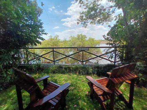 two wooden benches sitting in the grass near a bridge at Caprivi River Lodge in Katima Mulilo