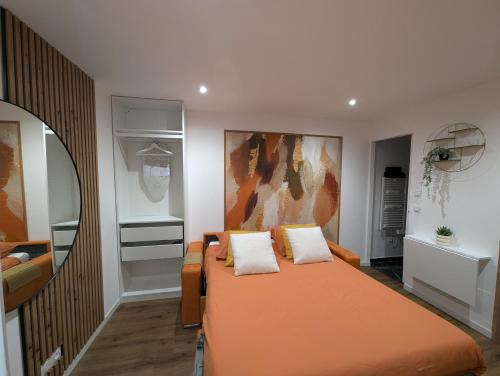 1 dormitorio con 1 cama naranja y 2 almohadas en Évasion Douceur, studio accueillant, près de Paris, en Villejuif